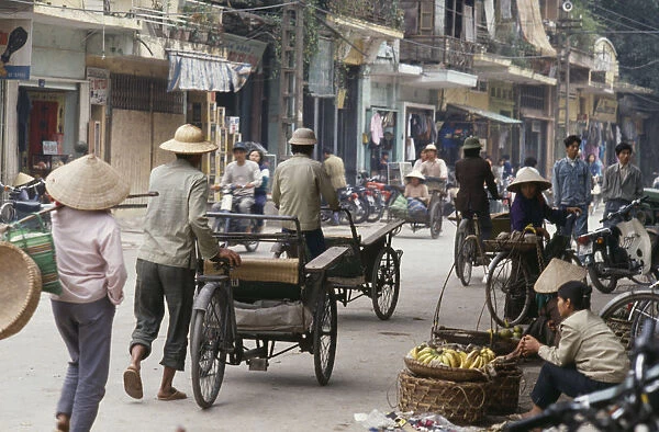 20043776. VIETNAM North Hanoi Busy street with bicycles cyclos and street vendors