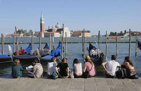 Italy, Veneto, Venice, gondolas & people sitting on waterside at Il Molo