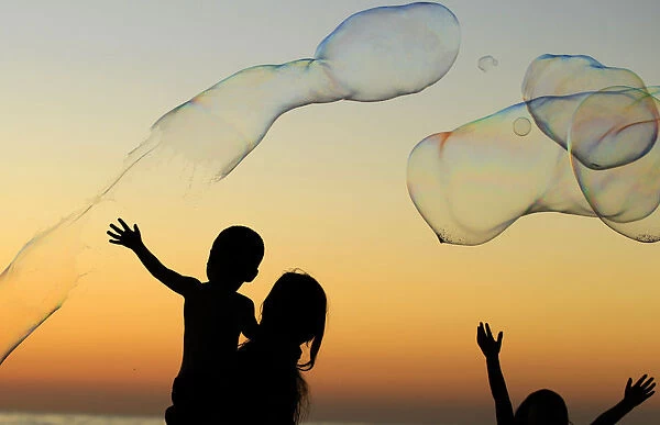 Children play with giant bubbles as the sun sets at Moonlight Beach in Encinitas
