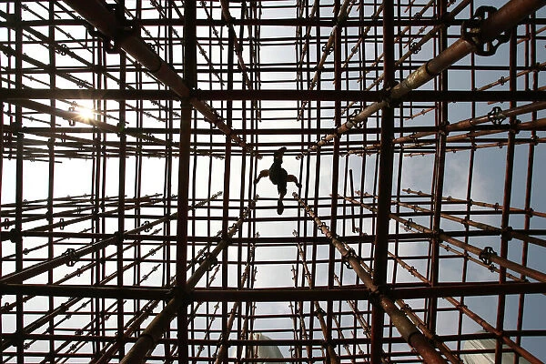 A labourer walks across scaffolding at a construction site in Wuhan
