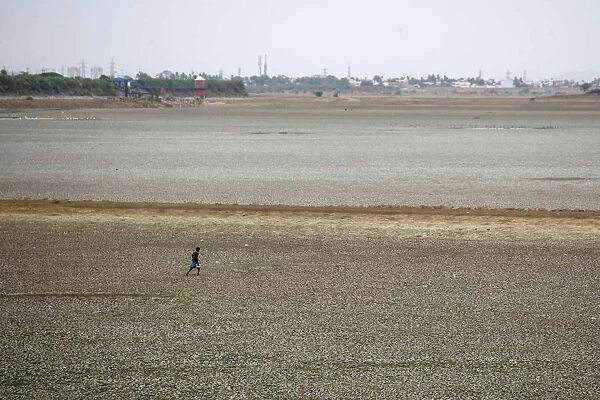 A man walks through the dried-up Puzhal reservoir, on the outskirts in Chennai