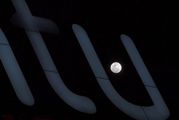 A full moon super moon is seen through a luminous sign in Siero