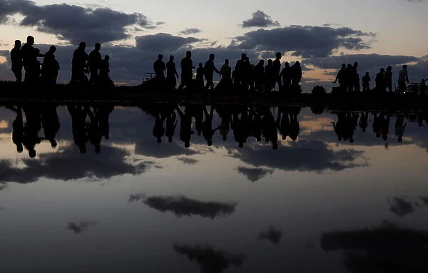 Palestinian demonstrators are reflected in rain water after attending a protest at the