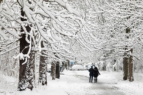 People walk on a snow-covered path in the Bois de Vincennes in Paris, France