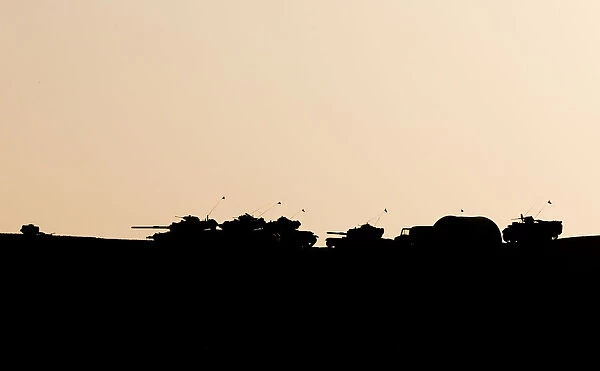 Turkish military are silhouetted on the top of a hill close to the border line between