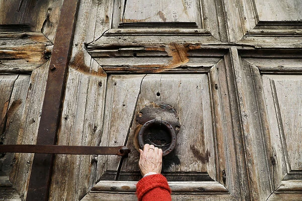 A worshipper touches the closed doors of the Church of the Holy Sepulchre in Jerusalem's