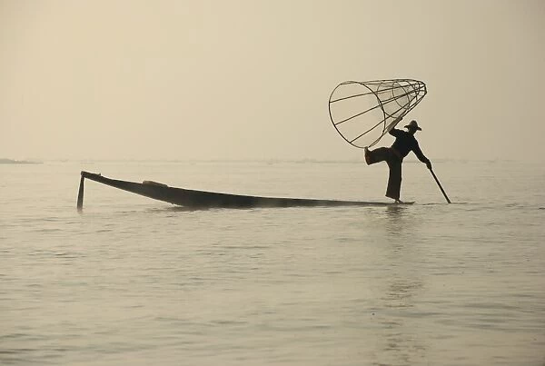 Traditional fisherman with fish trap in boat, Inle Lake, Shan State, Myanmar, January