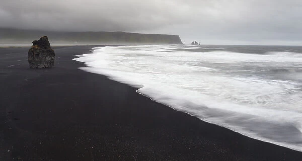 Europe, Iceland, Vik. Basalt column rises from black sand beach on rainy day. Credit as