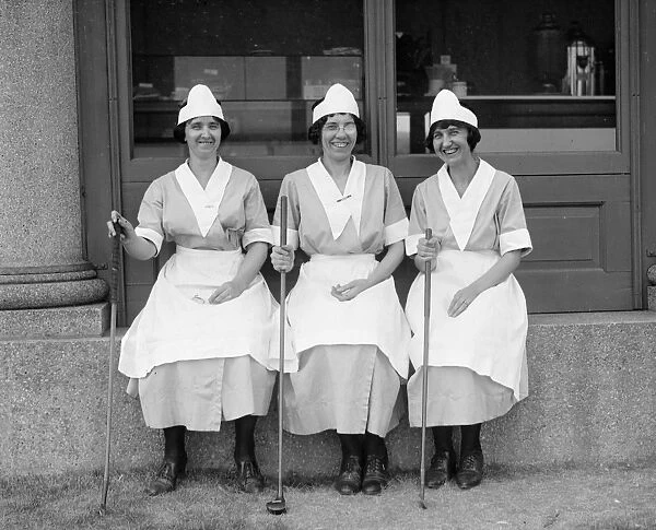 GOLF: WOMEN, 1923. Three women wearing uniforms and holding golf clubs. Photograph