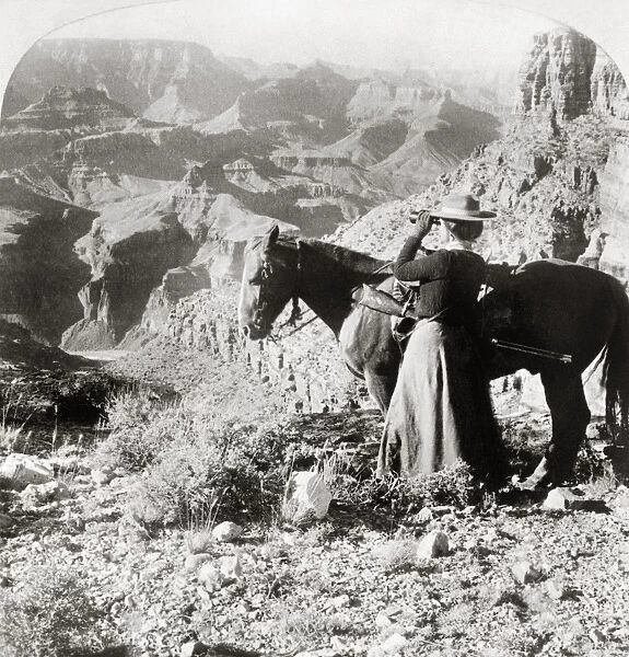 GRAND CANYON: SIGHTSEER. A woman standing next to a horse as she looks out across the Grand Canyon in Arizona through a pair of binoculars. Stereograph, 1903