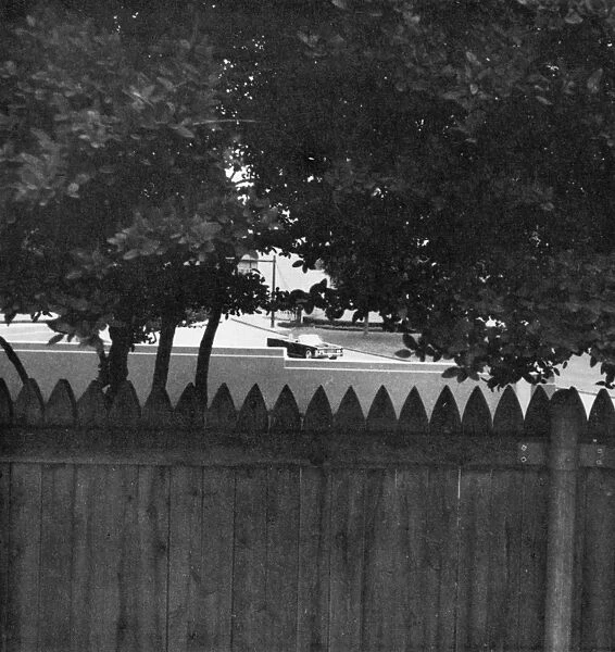 Photograph of what would have been a gunmans view of the John F. Kennedys car if he had been hidden behind the fence on the grassy knoll at the time of Kennedys assassination in Dallas, Texas, 22 November 1963. Photograph by Stephen White, 1968
