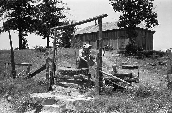 TENANT FARMER, 1939. A tenant farmer drawing water at a well on a sixty-acre farm