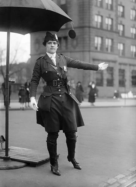 TRAFFIC COP, 1918. A female traffic cop directing traffic under an umbrella stand