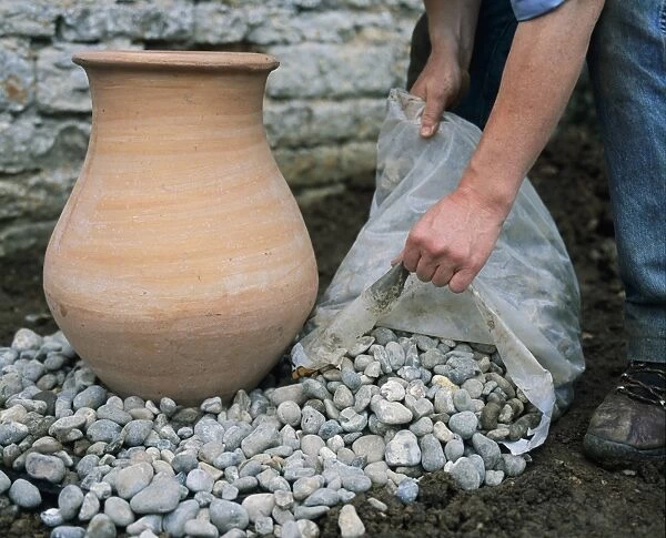 Arranging pebbles around terracotta urn (making a water feature), close-up