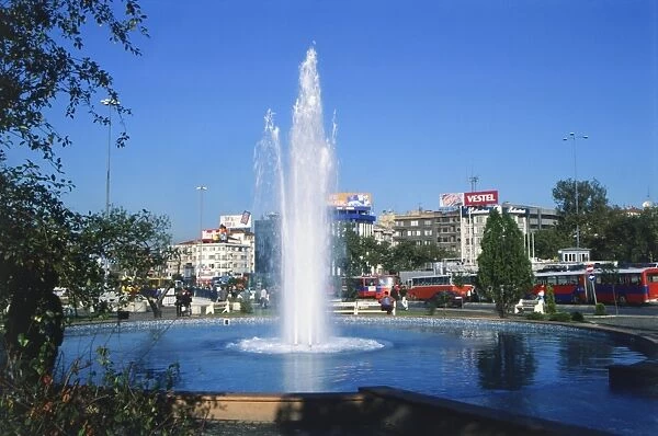 Asia, Turkey, Istanbul, fountain in the park at the centre of Taksim Square, water shooting up into air, buildings and vehicles in background