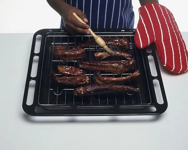 Boys hand brushing spare ribs with basting brush, close-up
