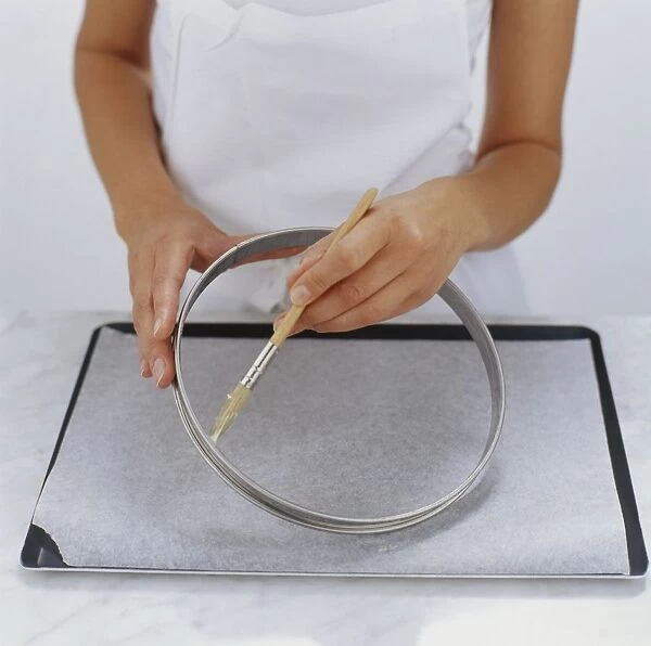 Chef using basting brush to butte tart ring on baking tray