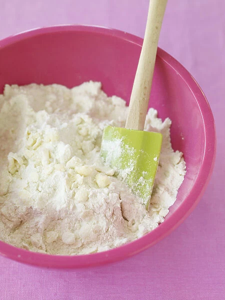 Flour, butter and rubber spatula in mixing bowl, close-up, view from above