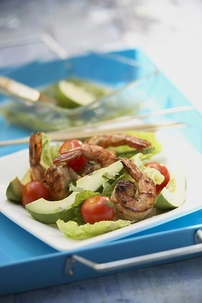 Grilled chilli prawns, lettuce and avocado salad with lime-cumin dressing on a blue serving tray