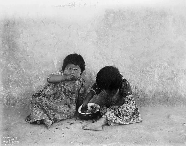 Two Hopi girls seated on ground eating melon, c1900. Photograph by Edward Curtis (1868-1952)