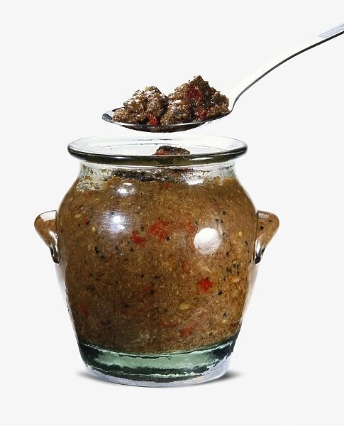 Jar of pickled venison and chillies and a spoon held above the jar