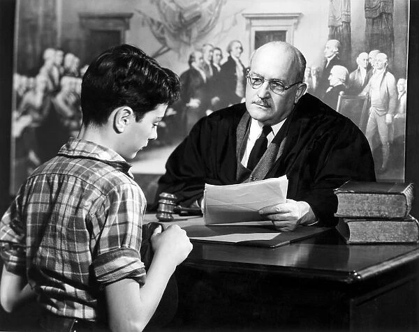 Judge sitting at his desk talking to a boy