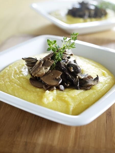 Two portions of porcini polenta, garnished with sprigs of thyme, close-up