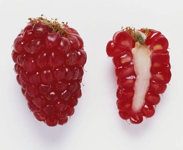 A whole raspberry beside a cross section of a raspberry