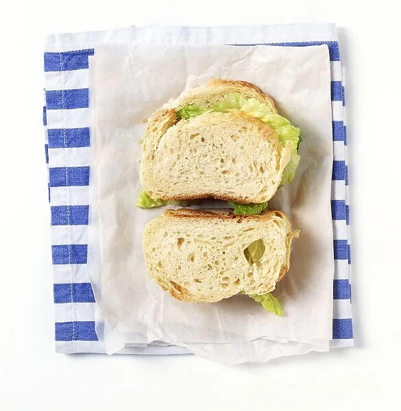 Salad sandwich on greaseproof paper and napkin, view from above