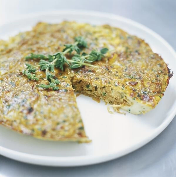 Sweet onion frittata garnished with fresh oregano served on a plate, one slice removed