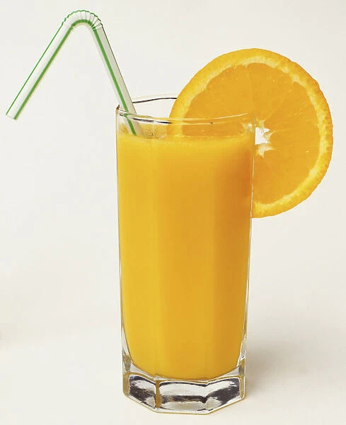 Tall glass of orange juice with straw and segment of orange