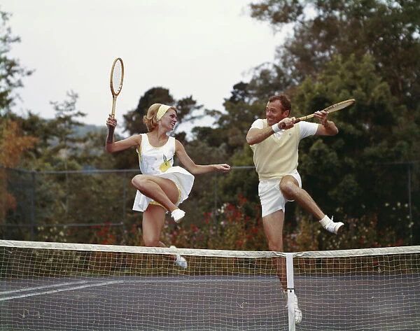 Couple jumping on tennis court, smiling