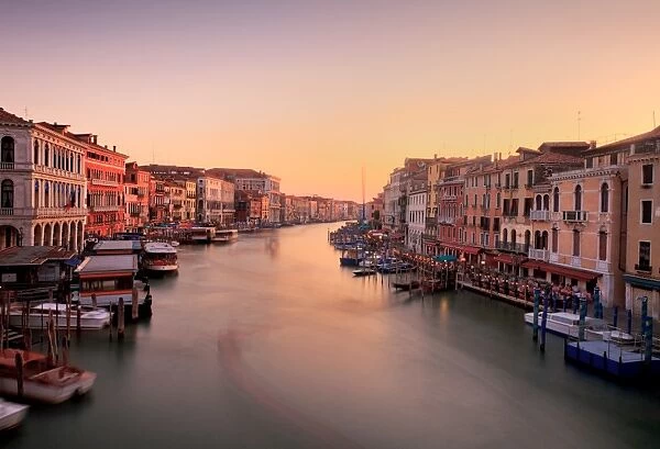 Evening glow. Venetian canal side palaces around Rialto Bridge glow in