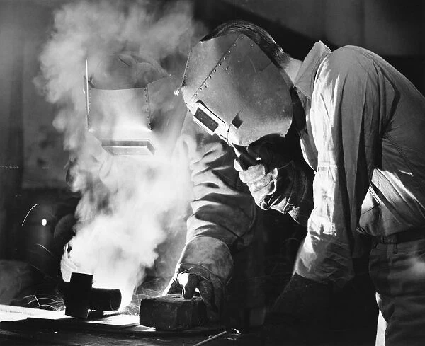 Two men welding, holding protective masks, (B&W)