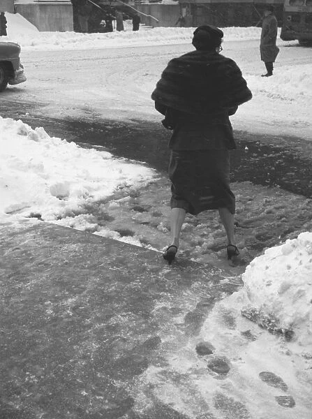 Woman crossing street in winter, (B&W), (rear view)