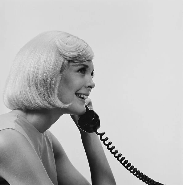 Young woman using telephone, smiling