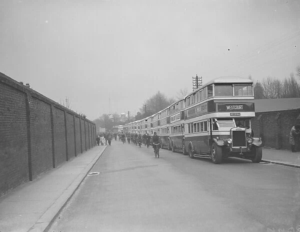 Buses parked on the road outside Chatham dockyard. Dock workers cycling past