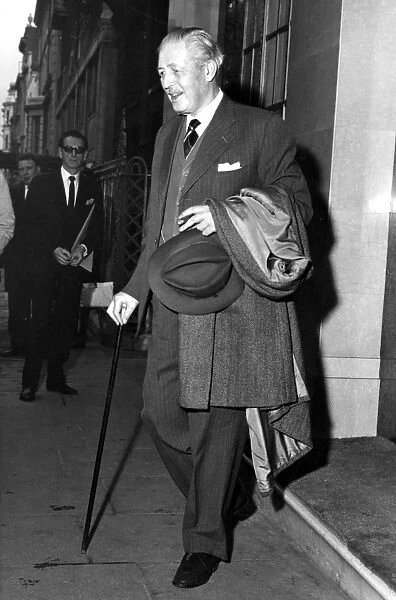 Harold Macmillan with walking stick and cigar leaving Claridges Hotel, West London
