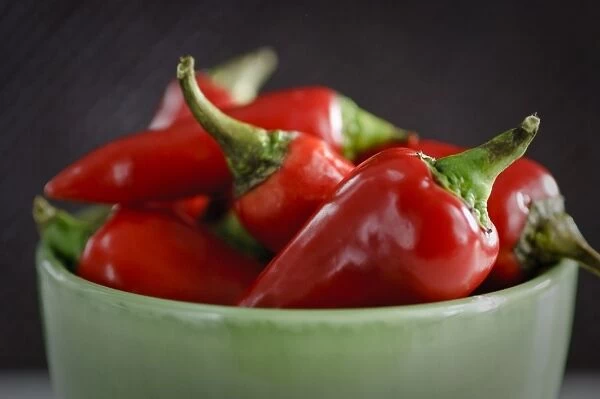 Shiny red chilli peppers in green bowl. Shorter depth of field. credit: Marie-Louise