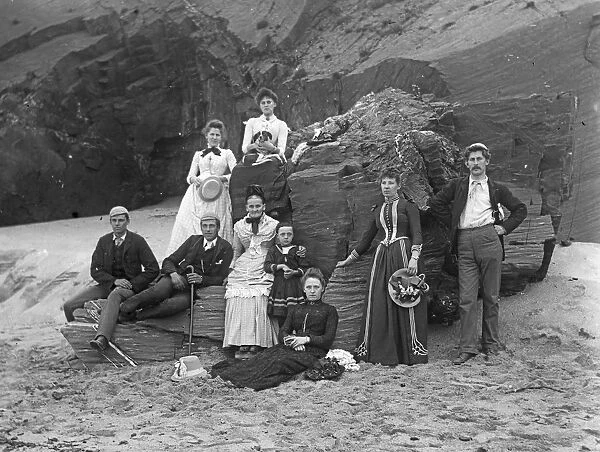 Group of people posed below cliff at Padstow, Cornwall. Probably 1890s or early 1900s