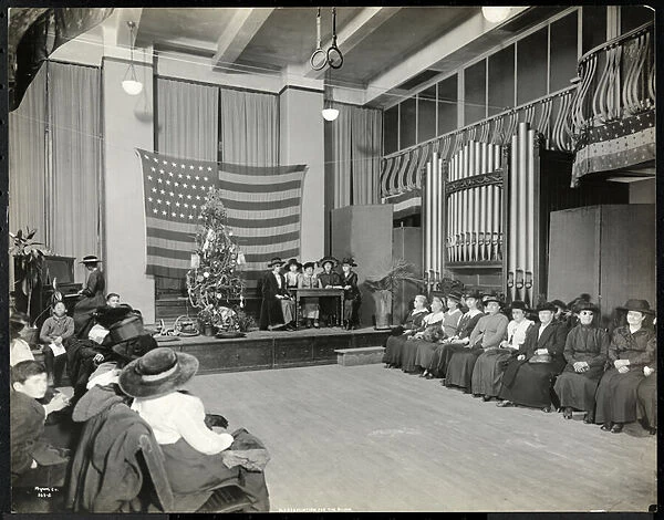 People in an auditorium at the New York Association for the Blind with Christmas tree
