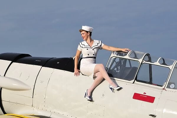1940s style pin-up girl sitting outside the cockpit of a T-6 Texan