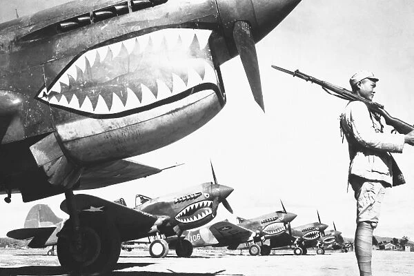 A Chinese soldier guards a line of American P-40 fighter planes during WWII
