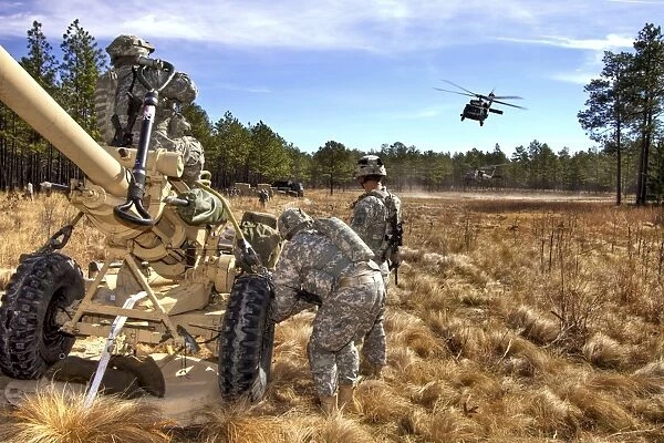 Paratroopers prepare to hook up an M119A2 howitzer to a UH-60M Black Hawk