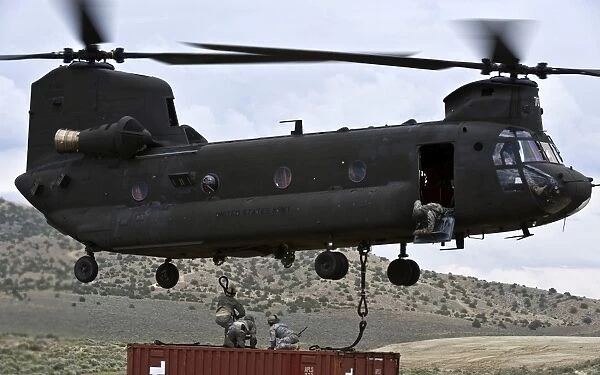 Personnel attach a storage container to a CH-47 Chinook helicopter