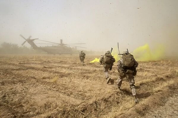 U. S. Marines sprint across a field to load onto a CH-53E Super Stallion