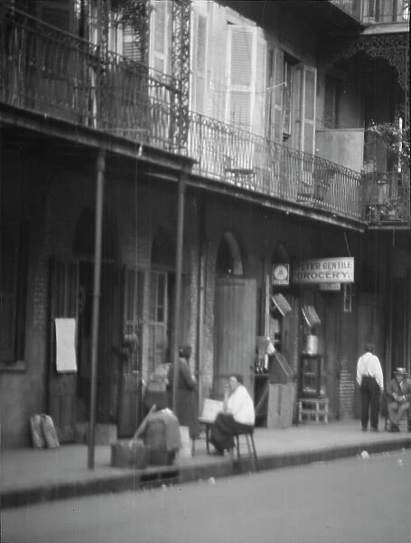 View from across street of people under a covered sidewalk, New Orleans, between 1920 and 1926. Creator: Arnold Genthe