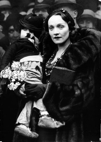 Marlene Dietrich (1931). The film actress famed for her performance in 'The Blue Angel'photographed with a child dressed as Charlie Chaplin on her arrival at Liverpool Street Station