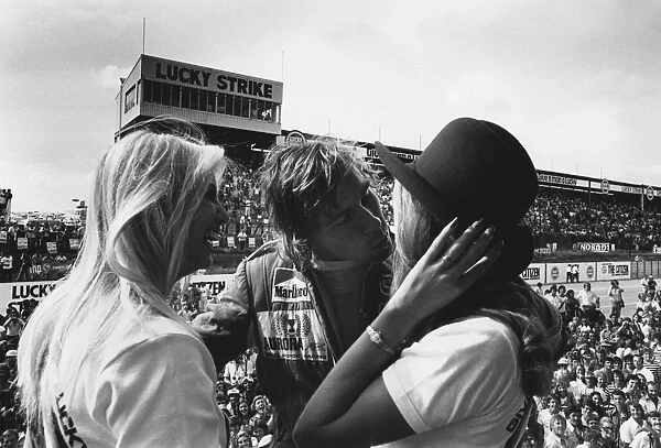 1976 South African Grand Prix: James Hunt, 2nd position, celebrates on the podium with some girls, portrait