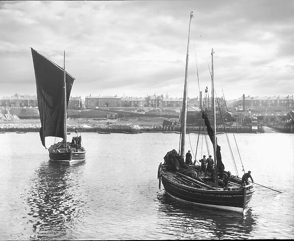 Magic lantern slide circa 1880, Victorian  /  Edwardian Social History. Two fishing boats leaving harbour with South Shields town in the background. Fishermen can be seen on their sail fishing boats preparing for sea; South Shields, Tyne and Wear, England